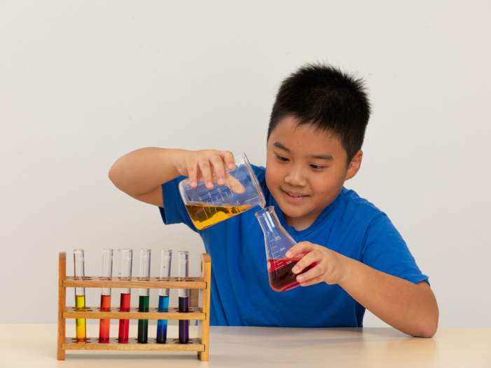 Boy pouring liquid from a beaker