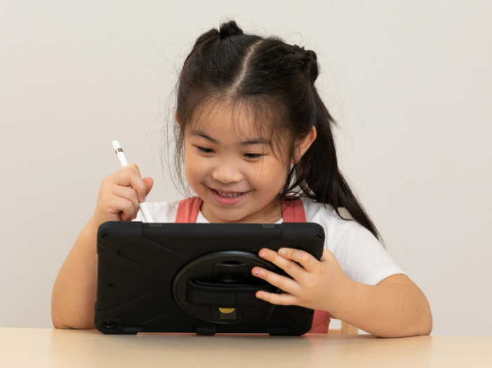 Girl looking at an ipad and writing