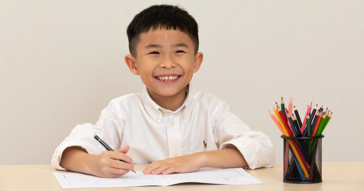 Boy writing on worksheet and smiling