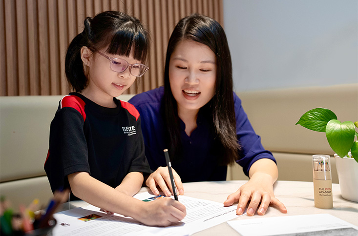 Female teacher helping student with writing in student care program.