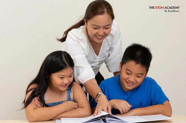 Teacher guiding two students during a tuition class.