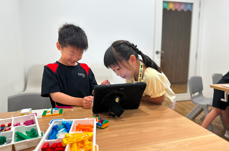 Two happy children reading a book together.